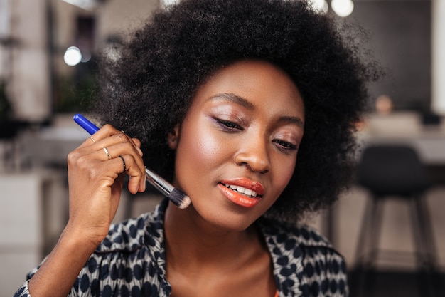 African american woman with curly hair looking positive while recording video