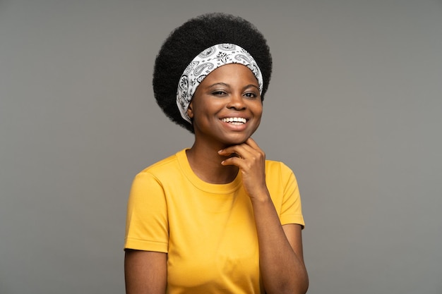 African American woman with headband performs sketch showing positive emotions in grey studio