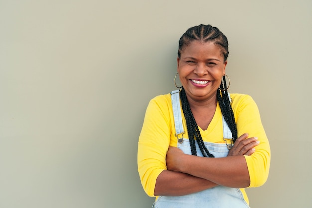 African American woman with long hair and braids standing on a gray wall - happiness