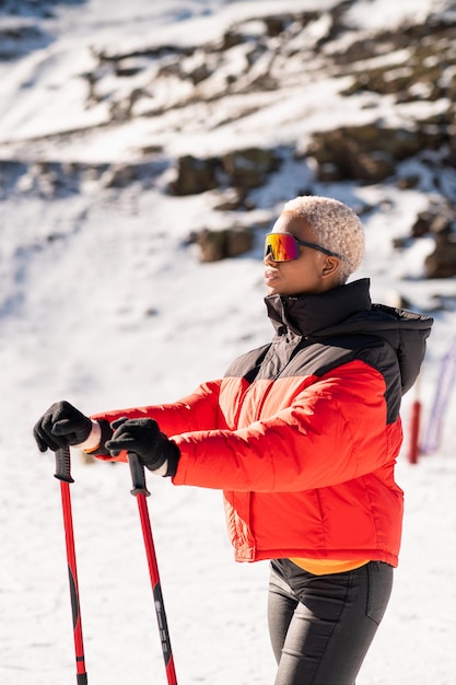 An African American woman with ski poles standing on a snowy mountain during winter