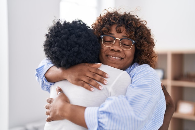 African american women mother and daughter hugging each other at home