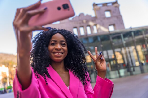 African american young woman in the city portrait of a young woman in pink jacket taking a selfie