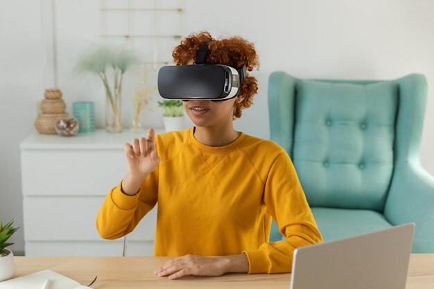 African american young woman wearing using virtual reality metaverse vr glasses headset at home girl