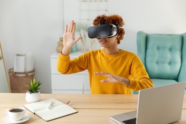 Photo african american young woman wearing using virtual reality metaverse vr glasses headset at home girl