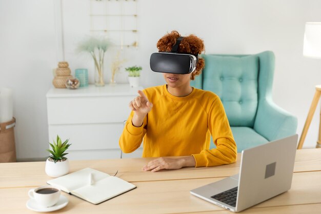 African american young woman wearing using virtual reality metaverse vr glasses headset at home girl