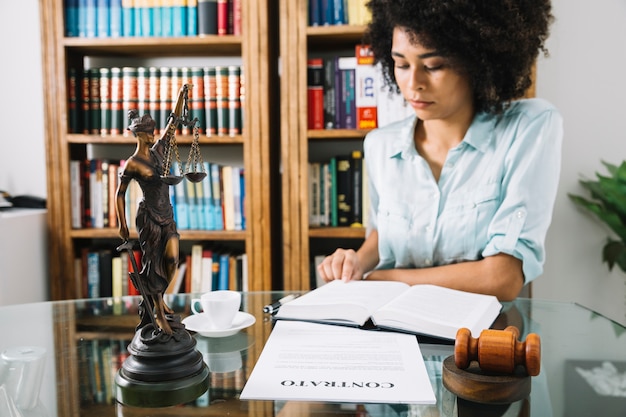 African American young woman with book at table with cup and document