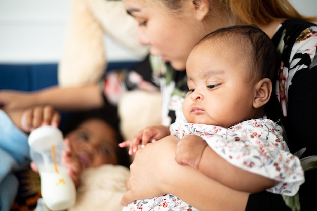 African baby girl live with her family in living room.Asian mother holding cute baby and take care her children on the sofa.