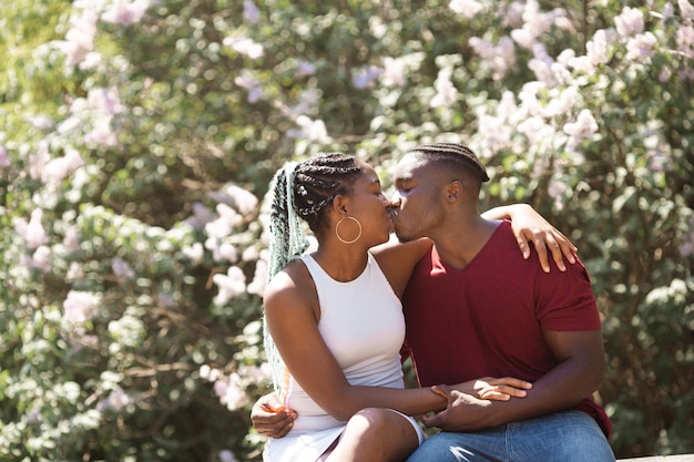 african beautiful young couple kissing in summer blooming park