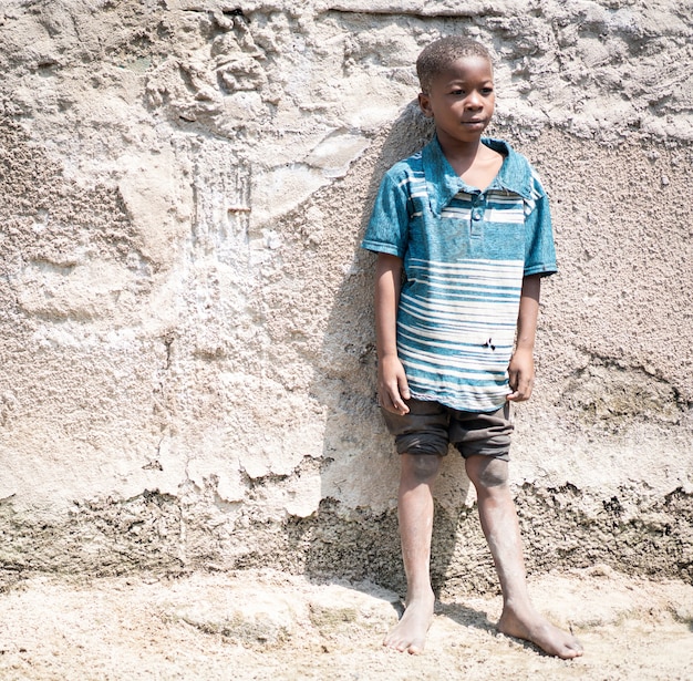 African black boy portrait standing near his poor house alone