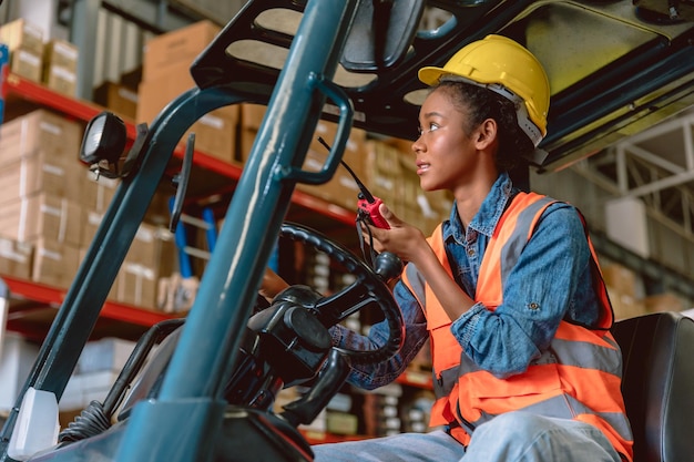 African black woman cargo worker work in warehouse working staff forklift driver command loading with ham radio