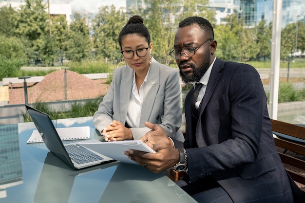 African businessman showing paper to asian female partner