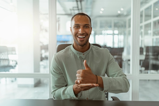 African businessman using sign language while talking online with client sitting in office