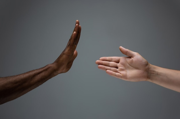 African and caucasian hands gesturing on gray studio background