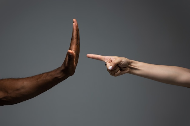 African and caucasian hands gesturing on gray studio background