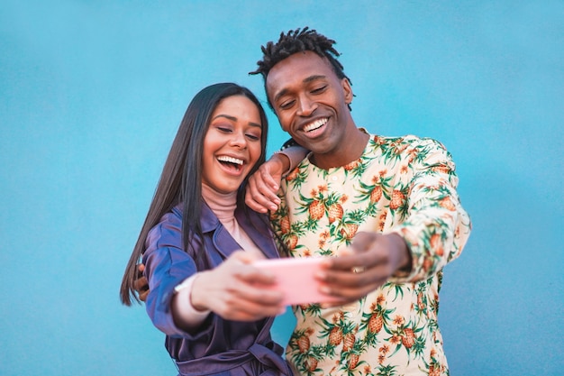 African couple taking selfie photo for social network story. Influencers people having fun with new trend technology