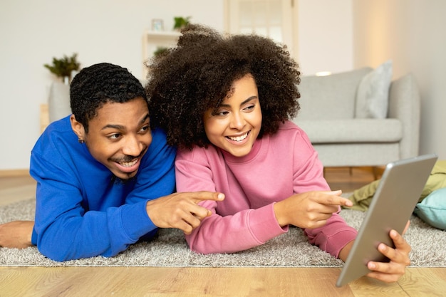 African couple using tablet engaging in digital fun at home