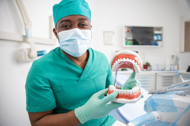 An african dentist holding a dentition teeth model in his hand dental health concept