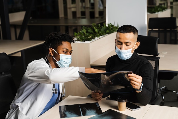 African doctor show xray asian patient Black surgeon analyzing x ray and diagnosis patient in medical clinic