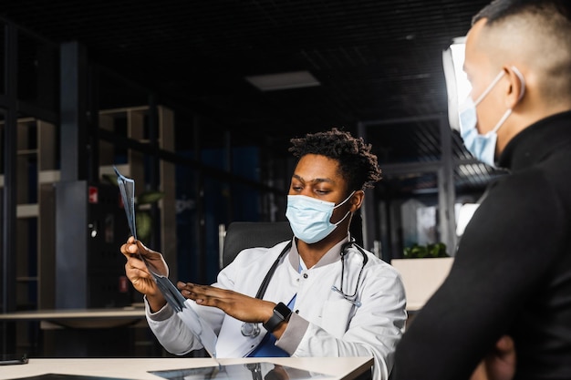 African doctor show xray asian patient Black surgeon analyzing x ray and diagnosis patient in medical clinic