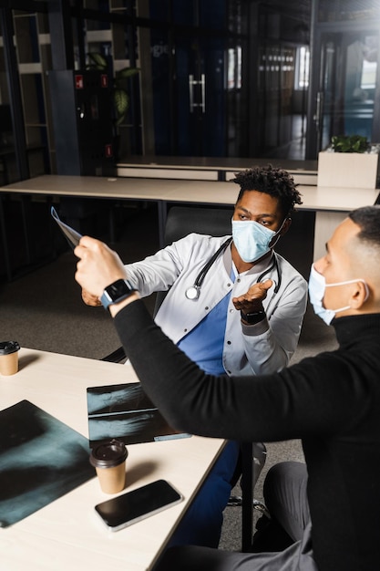 African doctor show xray asian patient Black surgeon analyzing x ray and diagnosis patient in medical clinic