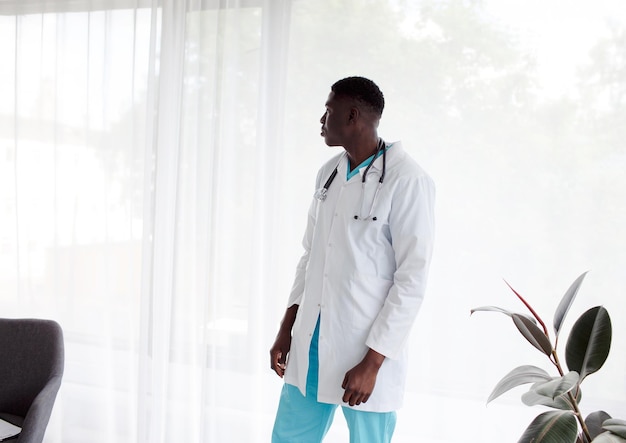 An African doctor stands near a large window