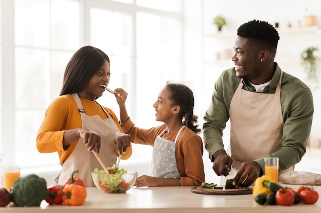 African family feeding each other having fun preparing salad indoor