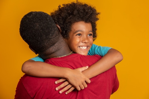 African Father and Son playing Superhero at the day time. People having fun yellow wall. Concept of friendly family.