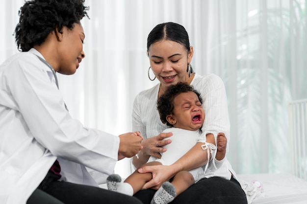 African female pediatrician hold stethoscope exam child boy patient visit doctor with mother