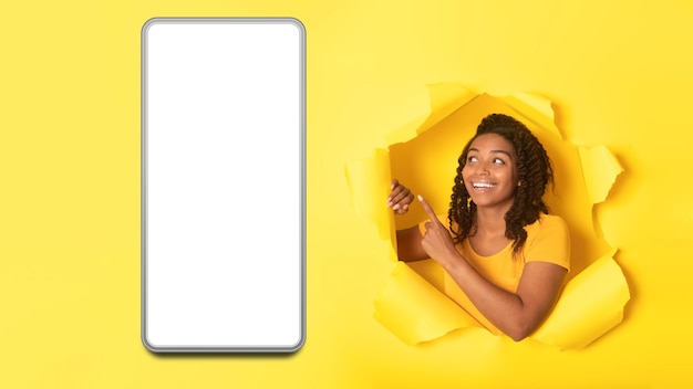 African Female Pointing At Huge Phone On Torn Yellow Background