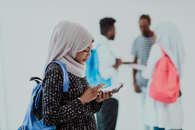 African female student with a group of friends in the background wearing traditional Islamic hijab clothes. Selective focus. High-quality photo