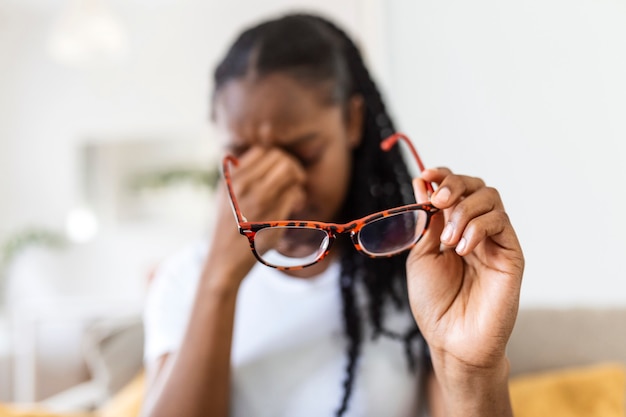 African girl in glasses rubs her eyes, suffering from tired eyes, ocular diseases concept