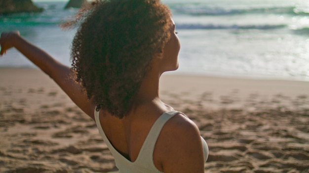 African girl stretching neck on sand beach close up Woman warmup at sunrise