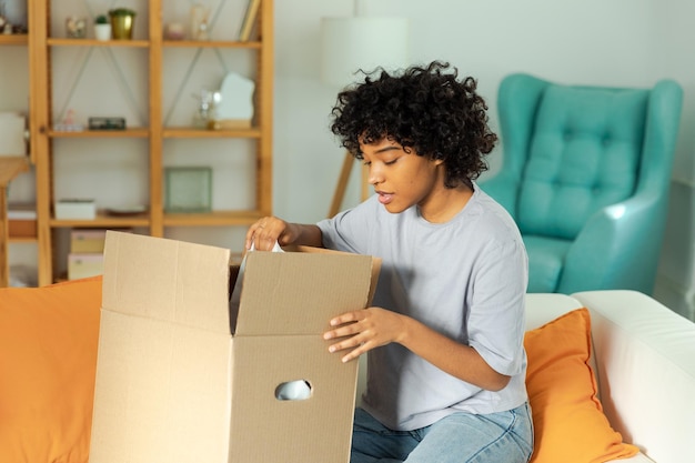 African girl unpacking delivery looking in box happy woman opening carton box female getting parcel