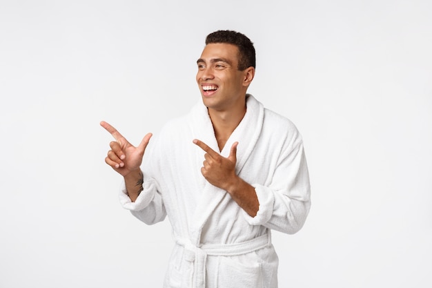 African guy wearing a bathrobe pointing finger with surprise and happy emotion.