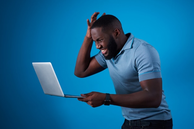 African guy with laptop and holding his head