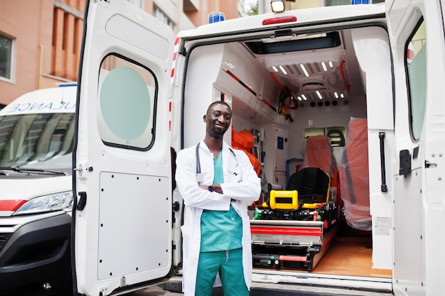 African male paramedic standing in front of ambulance car