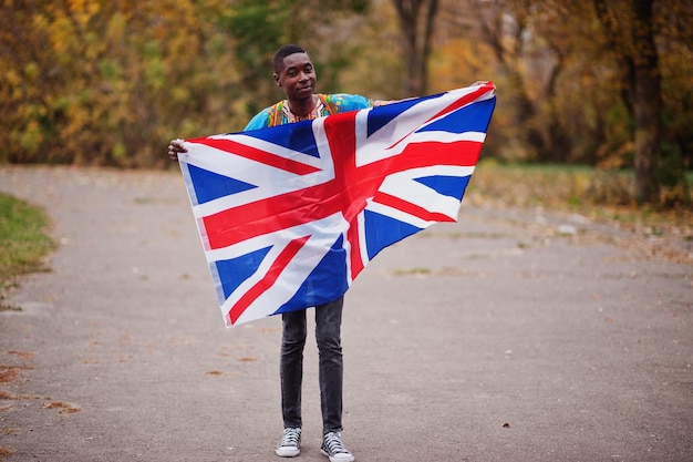 African man in africa traditional shirt on autumn park with Great Britain flag