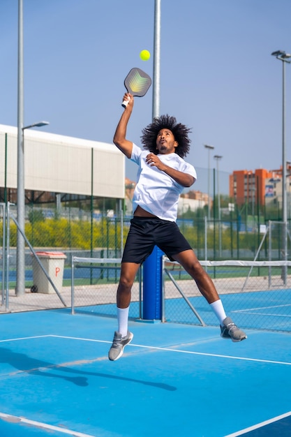 African man jumping to reach the ball playing pickleball outdoors