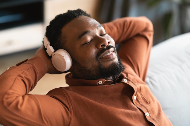 African Man Listening Music Wearing Headphones With Eyes Closed Indoor