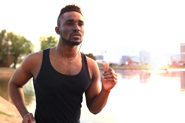 African man in sports clothing running while exercising, in beach outdoor portrait, at sunset or sunrise. Runner.