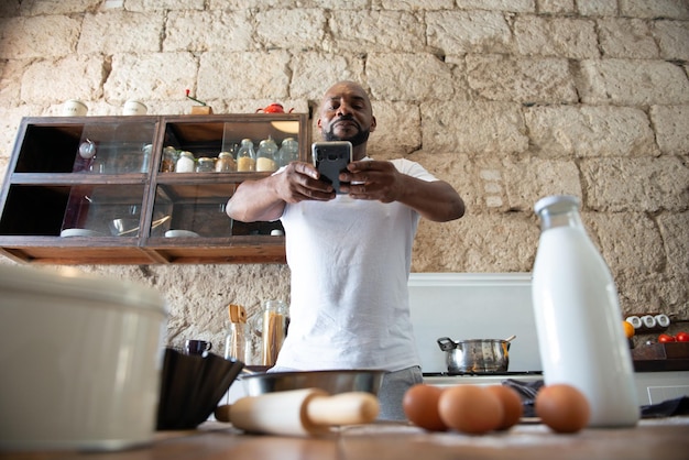 African man taking a photo of the food he is cooking in the kitchen of his house