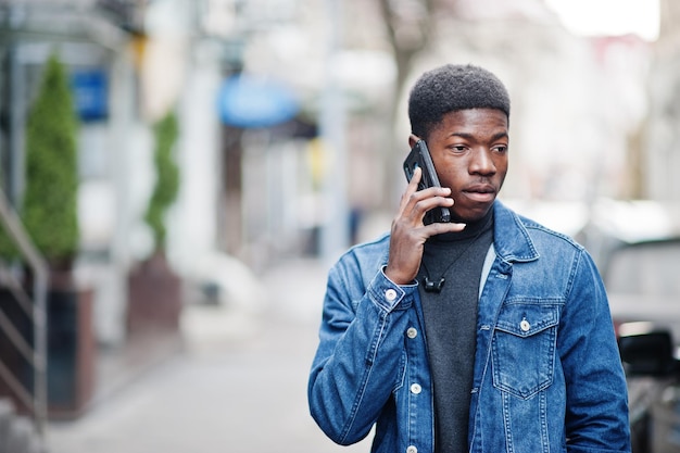 African man wear on jeans jacket posed outdoor speaking on phone