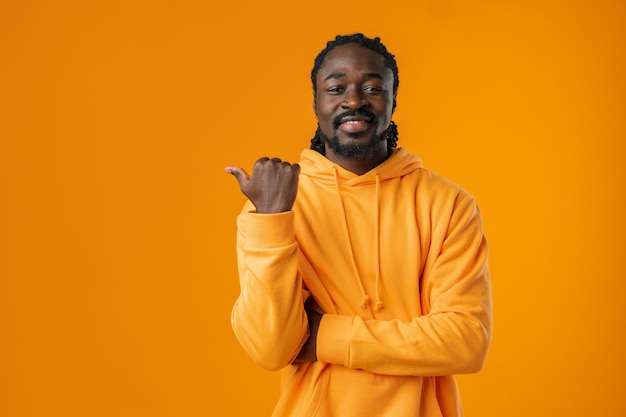 African man with beard pointing to copy space against yellow background