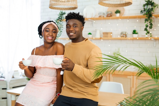 Photo african man and woman in the kitchen drinking tea together