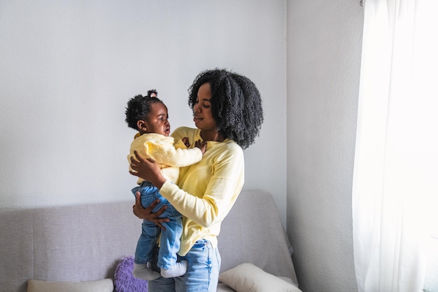 African mother comforting crying toddler in her arms at home