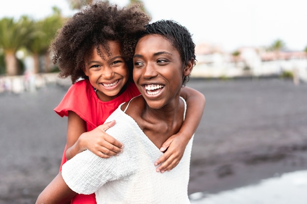 African mother and daughter having fun on the beach