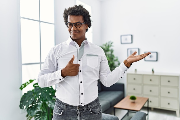 African psychologist man at consultation office showing palm hand and doing ok gesture with thumbs up, smiling happy and cheerful