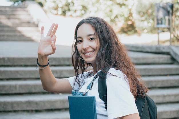 African student with backpack carrying books after study. Portrait of young african woman. Education concept. Trendy fashion style, holds a backpack, copy space. Smiling to camera