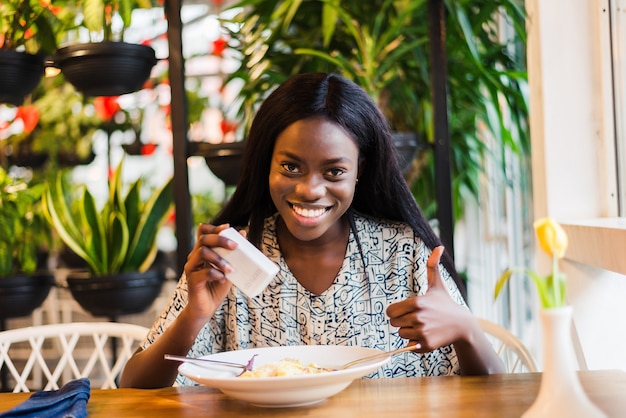 African woman adding salt to food in restaurant.