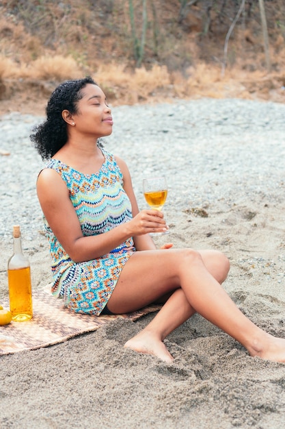 African Woman enjoying a glass of wine on the beach in the morning